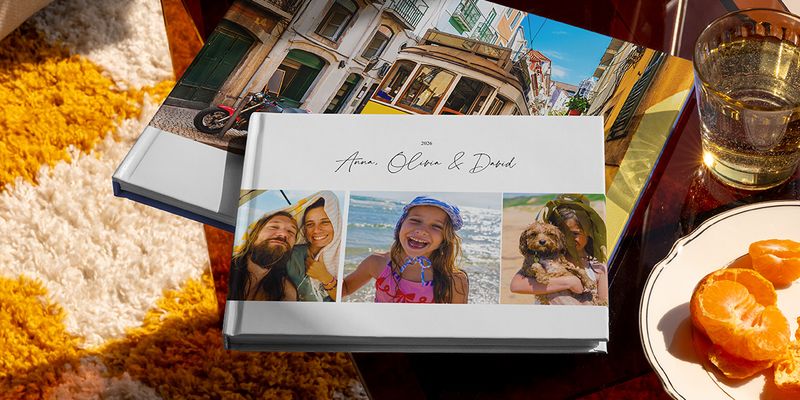 Zwei verschiedene posterXXL Reise-Fotobücher sind zusammen zu sehen, darunter ein Urlaubsfotobuch im Querformat mit Familienreisefotos auf dem Cover und ein weiteres mit einer Straßenbahn im Urlaubsmotiv – als Inspiration für verschiedene Reise-Fotobuch-Ideen.
